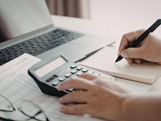 person writing and using a calculator